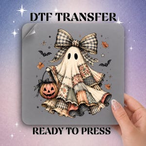 May include: A DTF transfer sheet featuring a ghost illustration with a large plaid bow, wearing a patchwork-style gown, and holding a jack-o'-lantern bucket. The design includes small bats, autumn leaves, and stars on a gray background with text.