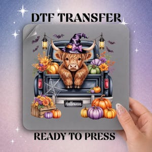 May include: A DTF transfer sheet featuring a Highland cow wearing a purple witch hat, sitting in the bed of a black pickup truck. The scene includes orange and green pumpkins, a wooden crate, lanterns, bats, and a spiderweb. The text reads DTF TRANSFER.