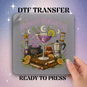 May include: A square DTF transfer sheet featuring the text Midnight Margaritas. The graphic displays a purple cocktail in a glass, a black cauldron, a moka pot, an hourglass, a golden key, and stacked books surrounded by citrus slices and stars.