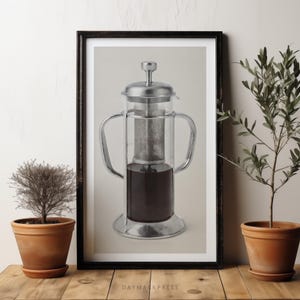 Könnte beinhalten: Ein gerahmter Druck einer French-Press-Kaffeebereiter aus klarem Glas mit Deckel, Griff und Boden aus silberfarbenem Metall. Das zylindrische Gefäß enthält eine dunkelbraune Flüssigkeit und einen feinmaschigen Metallfilter. Text DAYMARKPRESS.