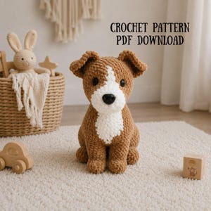 May include: A brown and white crocheted dog plush toy with black eyes and a black nose. The text CROCHET PATTERN PDF DOWNLOAD is visible in the upper right corner. The dog is made of soft yarn and is sitting in a neutral-coloured room.
