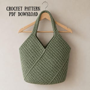 May include: A sage green crochet tote bag with a V-shaped front panel and two integrated handles, hanging on a wooden hanger. The text CROCHET PATTERN PDF DOWNLOAD is visible in the upper left corner of the image against a neutral background.