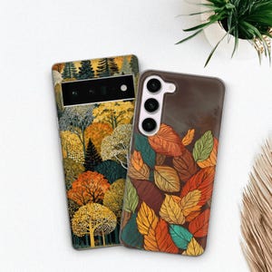 Può includere: Due cover rettangolari per smartphone. La cover a sinistra presenta un fitto paesaggio boschivo con alberi gialli, arancioni e verde scuro. La cover a destra mostra un motivo di foglie autunnali sovrapposte nei toni del rosso, arancione, giallo e verde acqua.