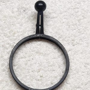 Puede incluir: Un soporte de filtro circular negro Hasselblad con un pomo esférico en la parte superior. El marco presenta un diseño dividido con una ranura de ajuste vertical. El texto "MADE IN SWEDEN" y "HASSELBLAD" está grabado en el anillo de plástico negro.