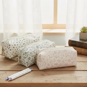 以下が含まれることがあります： ファスナー付きの長方形のペンケース3つ。それぞれ異なる花柄が特徴です。1つは白地に濃い青の花、もう1つは白地に青の花、3つ目はピンクの花柄がプリントされています。