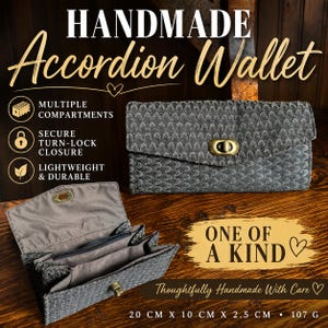 May include: A handmade accordion wallet featuring a dark grey textured exterior with a repeating scale pattern and a brass-toned turn-lock closure. The interior is lined with grey fabric and includes multiple compartments. Dimensions are 20 cm x 10 cm x 2.5 cm, weighing 107 g.