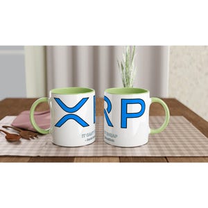 Op de afbeelding: Twee witte keramische mokken met lichtgroene binnenkanten en oren. De mokken zijn voorzien van het blauwe XRP-logo en de tekst "IT CAN'T BE THAT CHEAP - David Schwartz". Het ontwerp is op de voorzijde van elke mok gedrukt en toont de cryptovaluta branding.