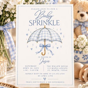 Peut inclure: Une carte d'invitation rectangulaire pour une fête prénatale avec une illustration de parapluie à carreaux bleus et blancs, des gouttes de pluie et des cœurs bleus. Le texte indique : Please join us for a baby sprinkle in honor of Josie.
