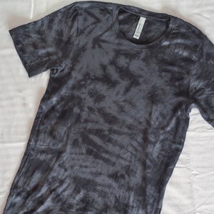 May include: A dark gray tie-dye t-shirt with a crew neck.