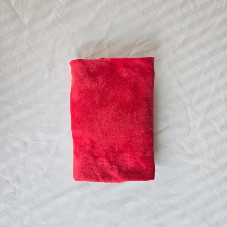 May include: A folded red velvet fabric. The fabric is smooth and soft.