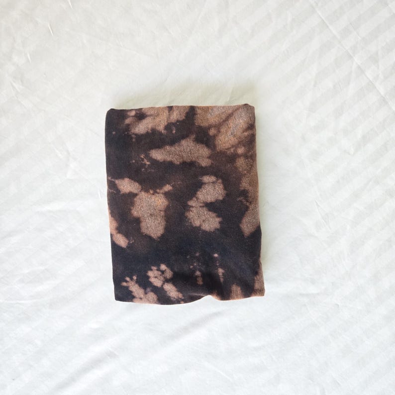 May include: A folded brown and black tie-dye fabric with a white background.