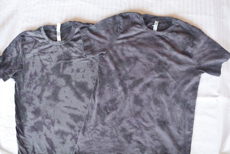 May include: Two gray tie-dye t-shirts with a crew neck and short sleeves.
