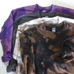 May include: Four sweatshirts in various shades of brown, white, gray, and purple with bleach tie-dye patterns.