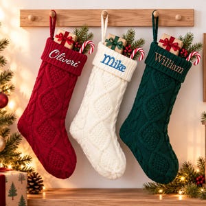 Puede incluir: Tres calcetines navideños de punto trenzado en rojo, blanco y verde oscuro, cada uno con un puño doblado bordado con los nombres Oliveri, Mike y William. Cada calcetín contiene una pequeña caja de regalo y un bastón de caramelo dentro.