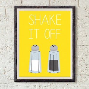 May include: A yellow framed print with the text "SHAKE IT OFF" in white. Two salt shakers are below the text, one with white salt and one with black pepper.