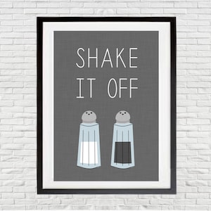 May include: A framed print with the text "SHAKE IT OFF" in white letters on a gray background. Two salt and pepper shakers are below the text, one with white contents and the other with black contents.