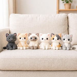 May include: Six small crocheted cat plushies arranged in a row. The cats feature various colours including dark grey, light orange, cream with brown points, solid white, calico, and grey tabby, all with large black eyes and stitched faces.