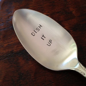 Puede incluir: Una cuchara de plata con las palabras "Dish It Up" grabadas en la parte delantera.