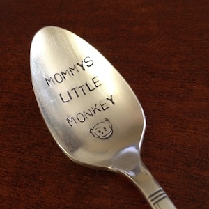 May include: A silver spoon with the words "Mommy's Little Monkey" engraved on it. A small monkey face is also engraved on the spoon.