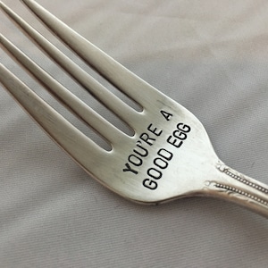 May include: A silver fork with the words "YOU'RE A GOOD EGG" engraved on the handle.