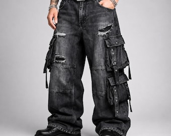 Peut inclure: Pantalon cargo en jean gris anthracite délavé avec une coupe large, de multiples grandes poches utilitaires à sangles bouclées et des détails déchirés. Le pantalon comprend une ceinture noire à clous et est porté avec des bottes noires épaisses.