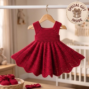 Peut inclure: Une robe sans manches en crochet rouge foncé avec une jupe évasée et un motif texturé, suspendue à un cintre en bois. Un badge circulaire dans le coin supérieur droit présente une illustration de cadeau et le texte SPECIAL GIFT INSIDE.