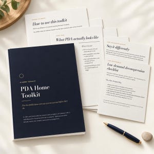 May include: A dark blue booklet titled PDA Home Toolkit with white text, accompanied by several white informational cards featuring black text and a dark blue pen. The cards include headings such as How to use this toolkit, What PDA actually looks like, Say it differently, and Low demand decompression checklist.