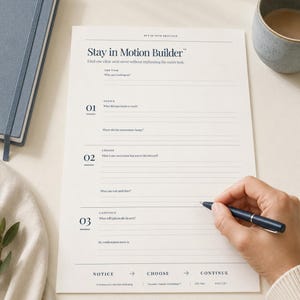 May include: A white paper worksheet titled Stay in Motion Builder with dark blue text. The form includes sections for The Task, Notice, Choose, and Continue, with numbered prompts and blank lines for writing. A dark blue pen rests on the paper.