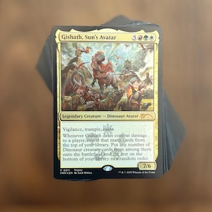 May include: A Gishath, Sun's Avatar trading card featuring a large dinosaur illustration, gold border, and text detailing its abilities. The card displays a 7/6 power and toughness, mana cost symbols, and the name Gishath, Sun's Avatar at the top.