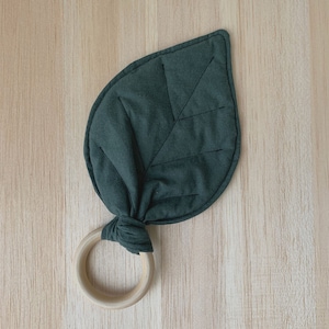 May include: A dark green fabric leaf-shaped teether with a wooden ring attached.