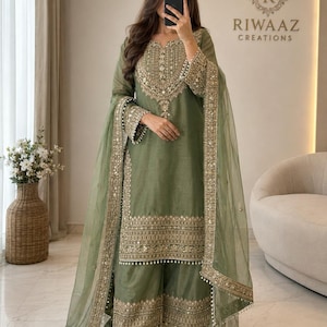 May include: An olive green three-piece ensemble featuring a long-sleeved tunic with intricate gold embroidery and mirror work, matching wide-leg trousers with a decorative hem, and a sheer matching dupatta with a gold embroidered border.