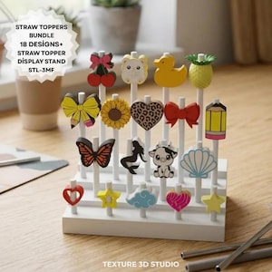 Op de afbeelding: Een witte displaystandaard met meerdere niveaus met 18 decoratieve rietjes-toppers in verschillende vormen, waaronder een kers, zonnebloem, luipaardprint hart, gele eend, ananas, vlinder, zeemeermin, koe, potlood, schelp en sterren met tekst STRAW TOPPERS BUNDLE.