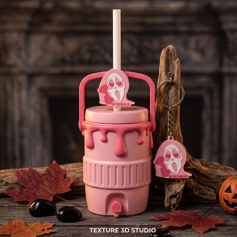 May include: A light pink beverage cooler with a spigot, a handle, and a white straw. The cooler features a pink topper of a ghost-like figure with heart-shaped eyes holding a phone, with the text DO YOU HANG UP. A matching keychain is attached.