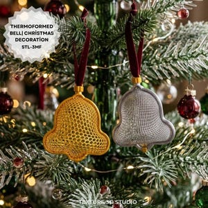 Op de afbeelding: Twee thermogevormde kerstdecoraties in de vorm van een bel, één goudkleurig en één zilverkleurig, met een fijnmazige roosterstructuur. Elke bel hangt aan een donkerrood fluwelen lint. De tekst THERMOFORMED BELL CHRISTMAS DECORATION STL-3MF is zichtbaar.