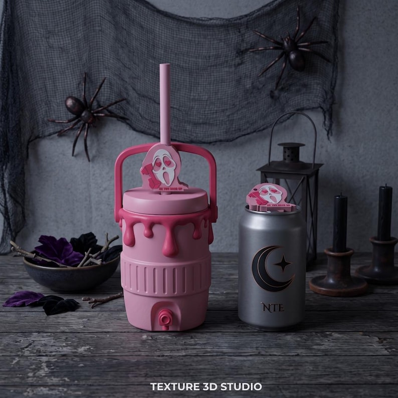 May include: A pink insulated beverage cooler with a handle, a straw, and a dripping paint design, featuring a Ghostface character topper with heart eyes. Beside it is a silver can-shaped tumbler with a crescent moon and star logo and text.