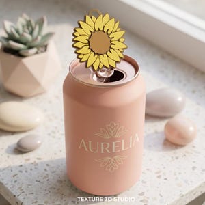 K&ouml;nnte beinhalten: Ein matter, pfirsichfarbener Dosenk&uuml;hler mit dem in Wei&szlig; aufgedruckten Namen AURELIA &uuml;ber und unter einem dekorativen floralen Liniendesign. Ein gelber Aufsatz in Sonnenblumenform steckt in der &Ouml;ffnung des Dosenk&uuml;hlers.