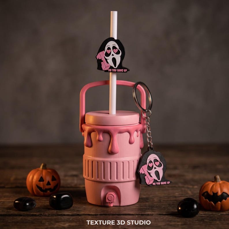 May include: A light pink beverage cooler with a drip design, a white straw, and a matching keychain. The straw and keychain feature a black and pink ghost character with heart-shaped eyes holding a phone, with the text NO YOU HANG UP.