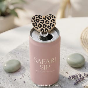 K&ouml;nnte beinhalten: Eine matte rosa Getr&auml;nkedose mit dem wei&szlig;en Text Safari Sip Wildheart Flavor. Ein herzf&ouml;rmiger Aufsatz mit einem schwarz-beigen Leopardenmuster ist an der silbernen Lasche oben auf der Dose befestigt und mittig &uuml;ber der &Ouml;ffnung platziert.
