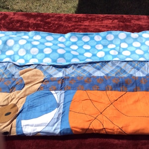 May include: A blue and brown patchwork quilt with a basketball, a dog, and white polka dots.
