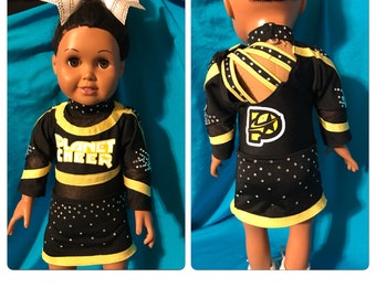 Könnte beinhalten: Ein schwarzes und gelbes Cheerleader-Outfit mit Strasssteinen und dem Schriftzug "Planet Cheer" auf der Vorderseite. Das Outfit hat einen gelben Saum und ein schwarz-gelbes Streifenmuster an den Ärmeln.