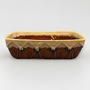 May include: A rectangular ceramic planter featuring a two-tone glaze with a dark brown base and a lighter beige top. The exterior surface displays a repeating geometric diamond pattern embossed into the clay, finished with a smooth, glossy glaze.