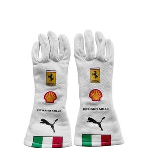 Peut inclure: Une paire de gants de course blancs arborant le logo Ferrari, un emblème Shell jaune et rouge, le texte RICHARD MILLE, un logo Puma noir et un drapeau italien au poignet. Les gants présentent une construction en tissu texturé.
