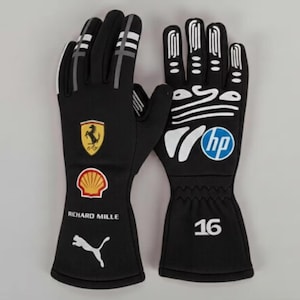 Peut inclure: Une paire de gants de course noirs avec des détails blancs sur les doigts, le numéro 16 et divers logos dont Ferrari, Shell, Richard Mille, Puma et HP. Les gants présentent un design épuré avec des accents blancs et un logo HP bien visible.