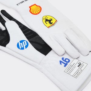 Peut inclure: Gants de course blancs avec logos Puma et Richard Mille noirs, un logo Shell jaune, un écusson Ferrari et un cercle bleu HP. Les gants présentent le numéro 16 en bleu et une étiquette de conformité FIA rectangulaire avec texte et logo Puma.