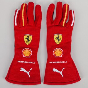 Pode incluir: Um par de luvas de corrida vermelhas com o logótipo do cavalo empinado da Ferrari, um emblema de concha Shell amarelo, o texto RICHARD MILLE em branco e um logótipo Puma branco no dorso de cada mão com detalhes amarelos e brancos nos dedos.