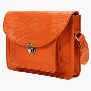 Puede incluir: Un bolso de hombro rectangular de color naranja brillante con una superficie texturizada y perforada. El bolso cuenta con una solapa frontal con borde redondeado, un bolsillo exterior y un cierre metálico plateado en la solapa frontal.