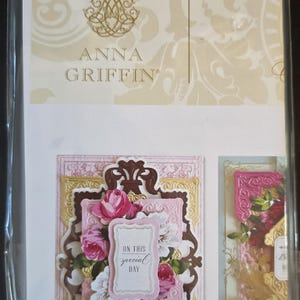 May include: A craft kit package by Anna Griffin featuring decorative paper die-cuts. The front displays a layered floral design with pink and white roses, ornate gold and brown frames, and a central label with the text ON THIS special DAY.