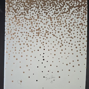 May include: A white rectangular book cover featuring a metallic gold polka dot pattern that is dense at the top and gradually fades toward the bottom. The cover includes a small hand-drawn heart and the handwritten name "Shelley" in black ink.