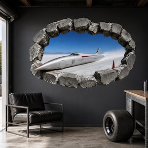 Può includere: Un adesivo da parete con un effetto 3D di un buco in un muro di pietra che rivela un veicolo argentato da record di velocità su una distesa salata. Il veicolo è contrassegnato dal numero 01 e dalla scritta Venturi. Un cono stradale arancione è visibile.