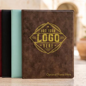 May include: A row of rectangular portfolios in various colors including brown, mint green, black, maroon, white marble, and tan. The front brown portfolio features a gold circular emblem with the text ADD YOUR LOGO HERE and Optional Name Here.